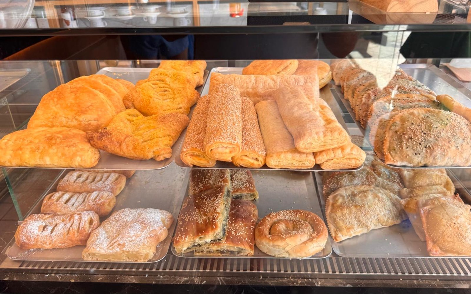 Display case of traditional Greek pastry — croissants, cheese rolls and phyllo pies at Bakery Kissamos
